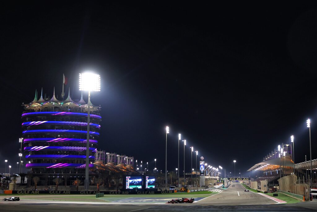 Night race at Bahrain International Circuit with lit tower.