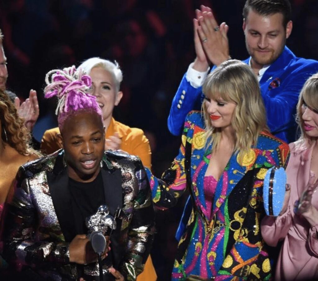 Awards ceremony with colorful outfits and trophy.