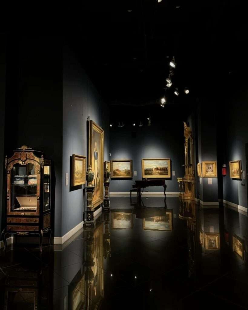 Dimly lit art gallery with paintings and reflections.