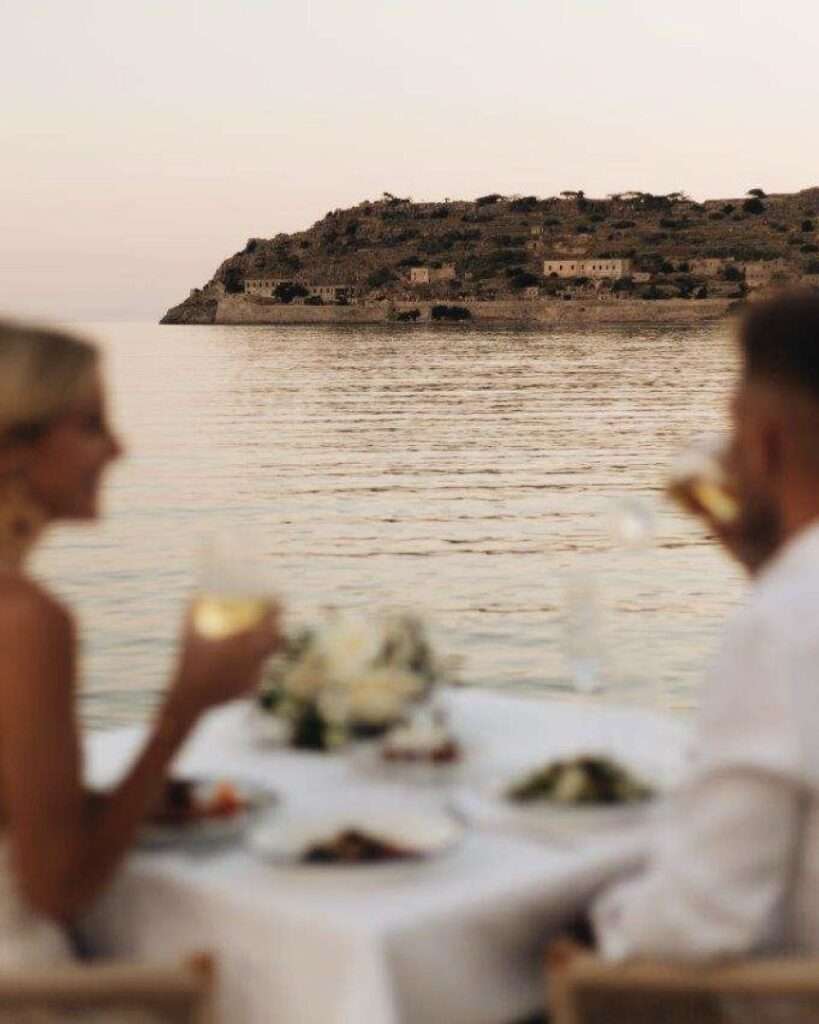 Couple dining by ocean with island view.