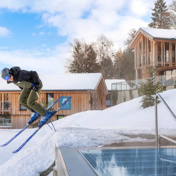 Skier jumping near snowy cabin scenery