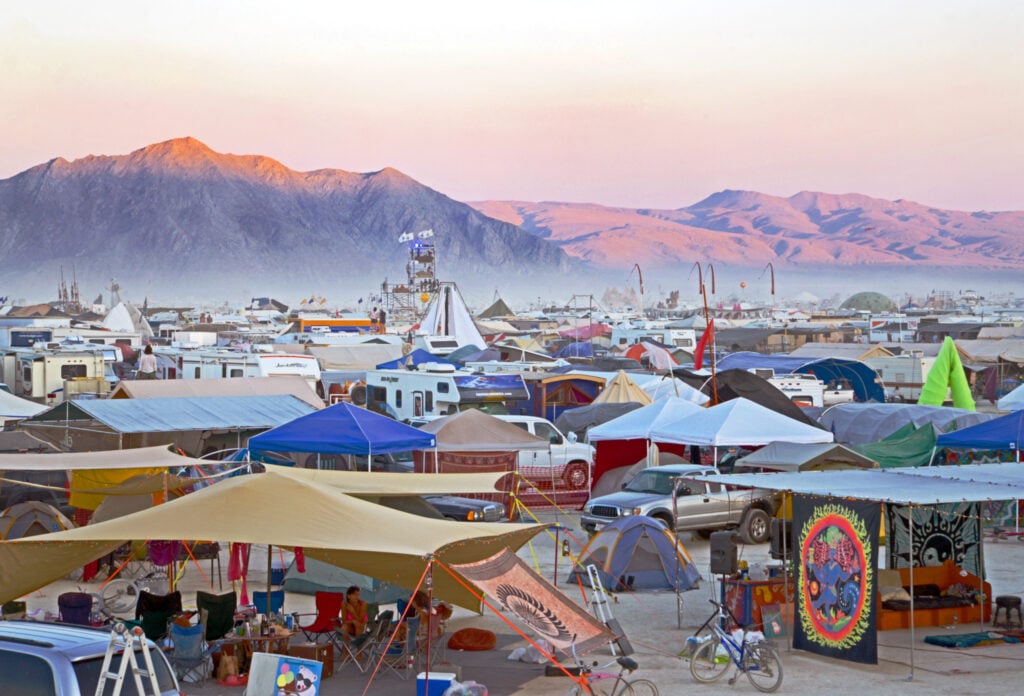 Colorful tents at desert festival with mountain backdrop.