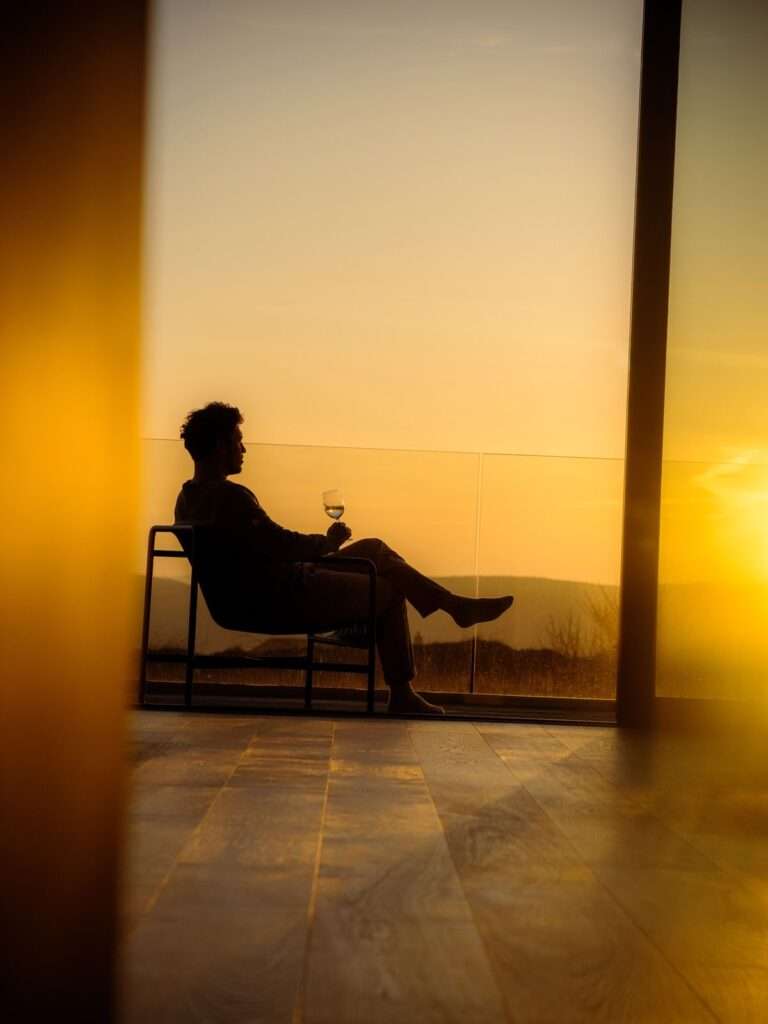 Person relaxing with wine at sunset.