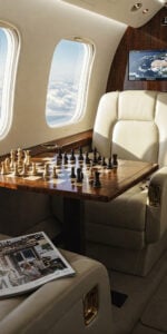 Airplane interior with chessboard and luxury seating.