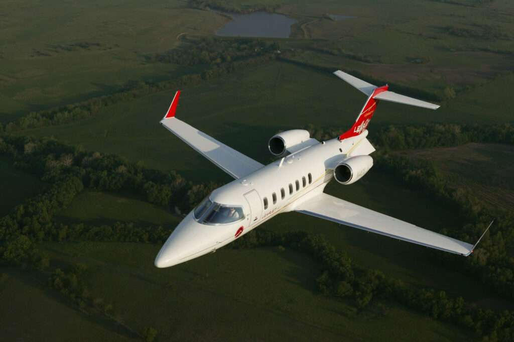 Private jet flying over green landscape