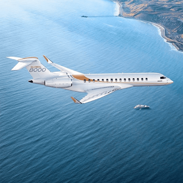 Private jet Global 8000 flying over ocean.