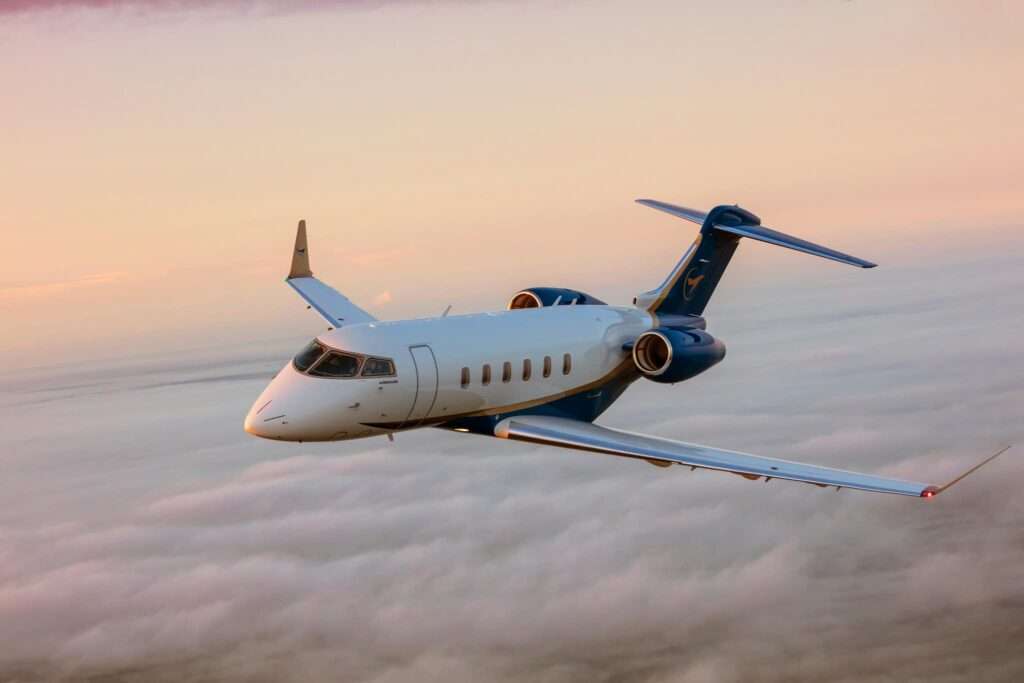 Private jet flying above clouds at sunset.