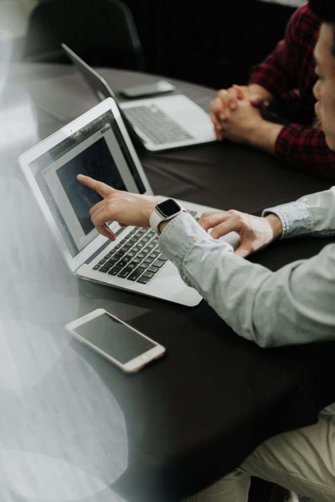 Man pointing at laptop screen during meeting.
