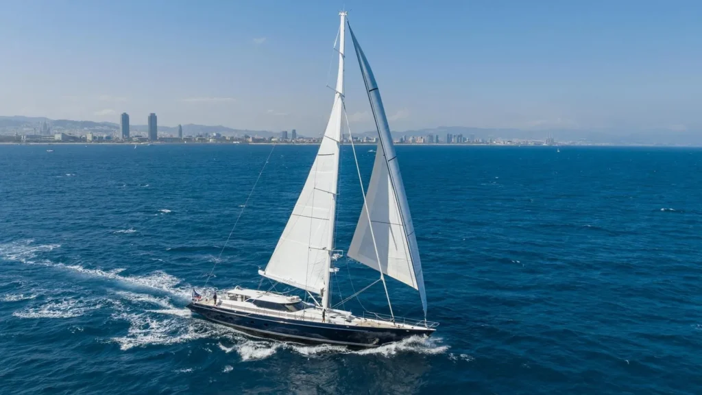 Sailboat cruising near city skyline on ocean.