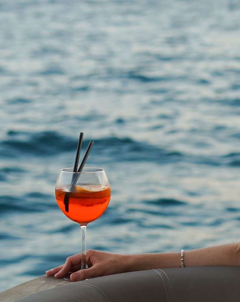 Hand holding cocktail by the ocean
