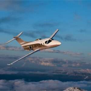 Private jet flying over cloudy mountains.