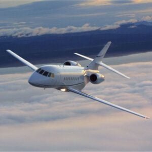 Private jet flying over clouds at sunset.