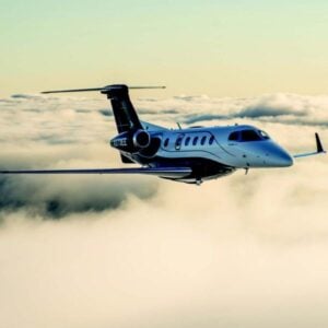 Private jet flying above clouds at sunset.
