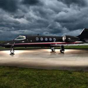 Private jet parked on runway under stormy sky.