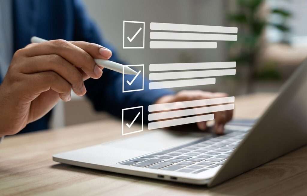 Hand checking boxes on digital checklist on laptop.
