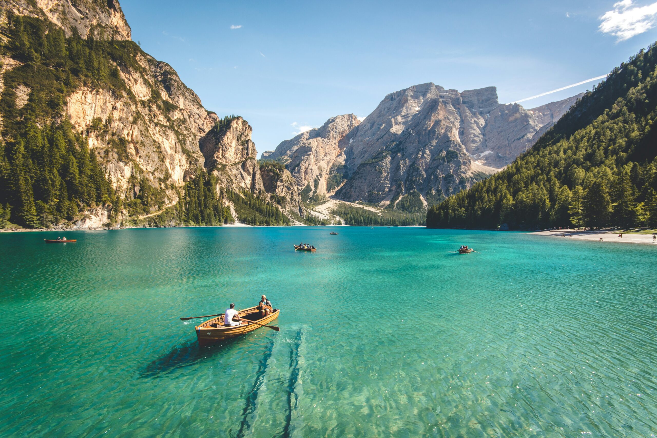 Boats on turquoise lake surrounded by mountains.