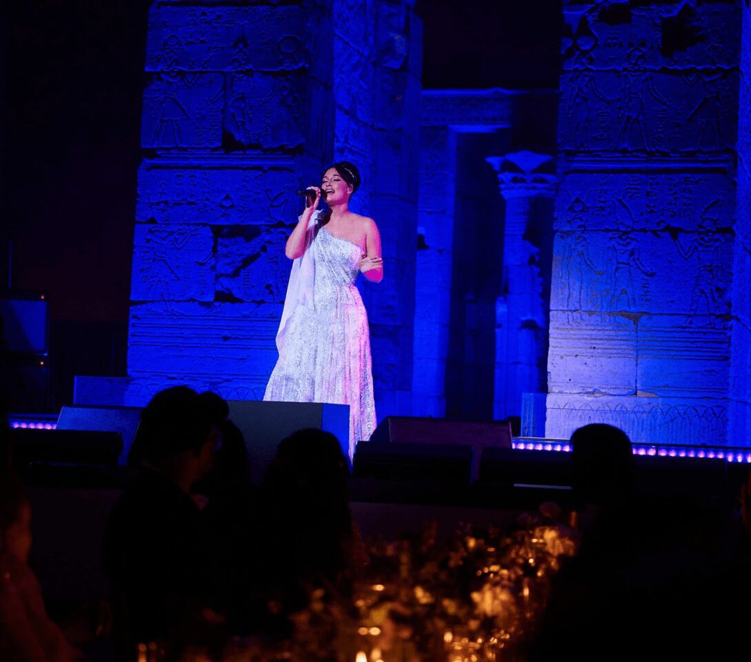 Singer performing on stage with blue lighting.