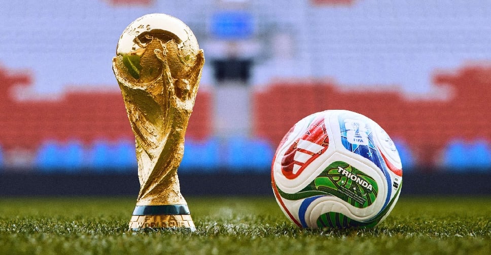 World Cup trophy and soccer ball on field.