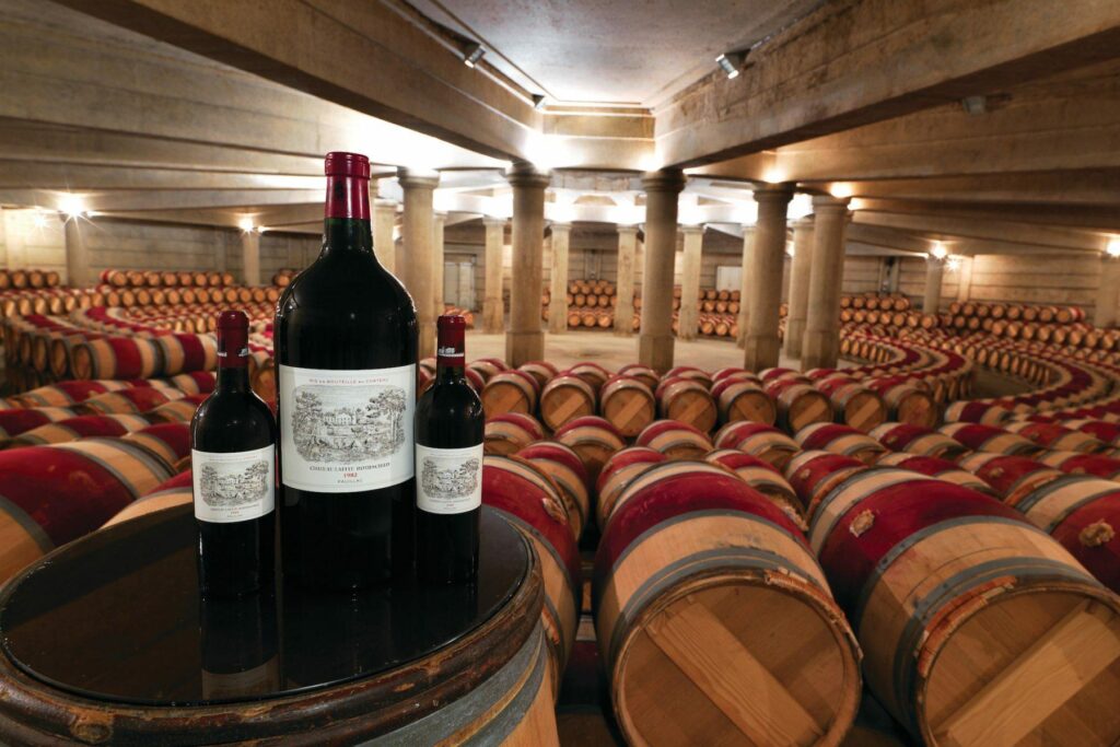 Wine bottles displayed in large barrel-filled cellar
