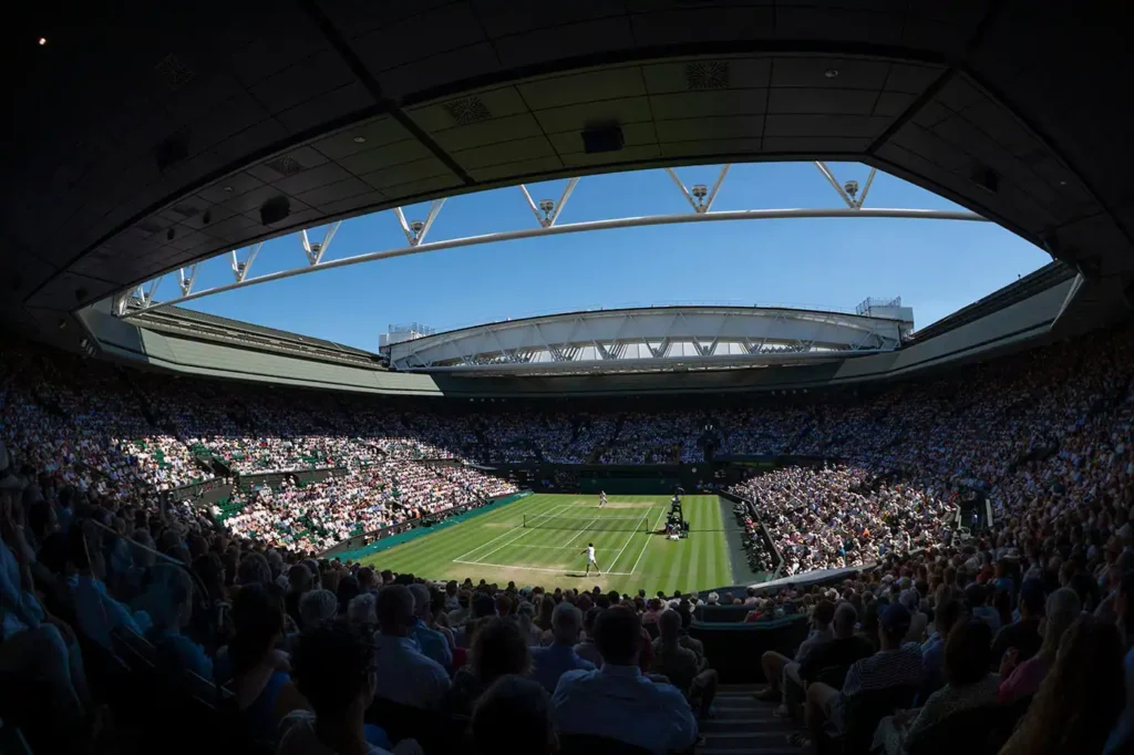 Crowded tennis match at Wimbledon under clear sky.