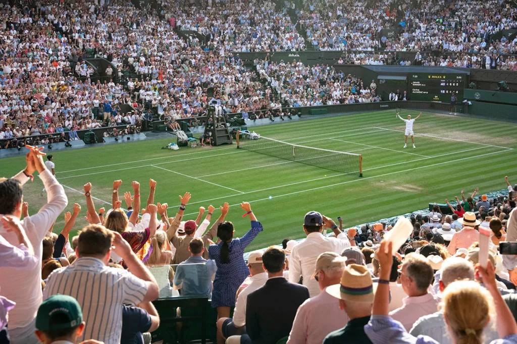 Crowd cheering at a tennis match victory celebration.
