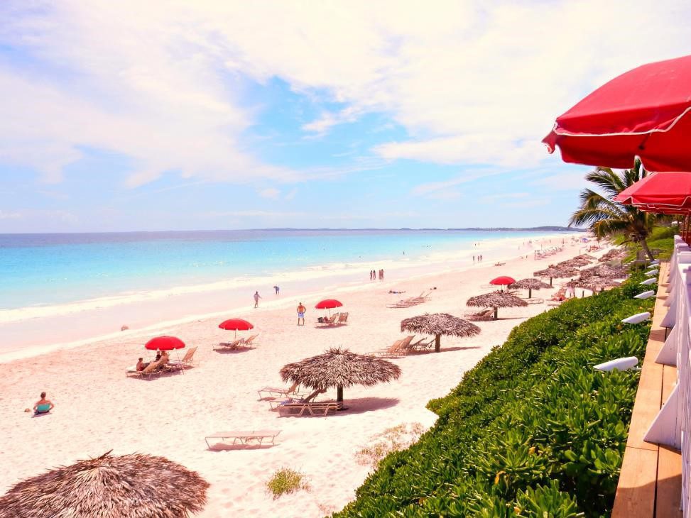 Sunny beach with red umbrellas and turquoise sea