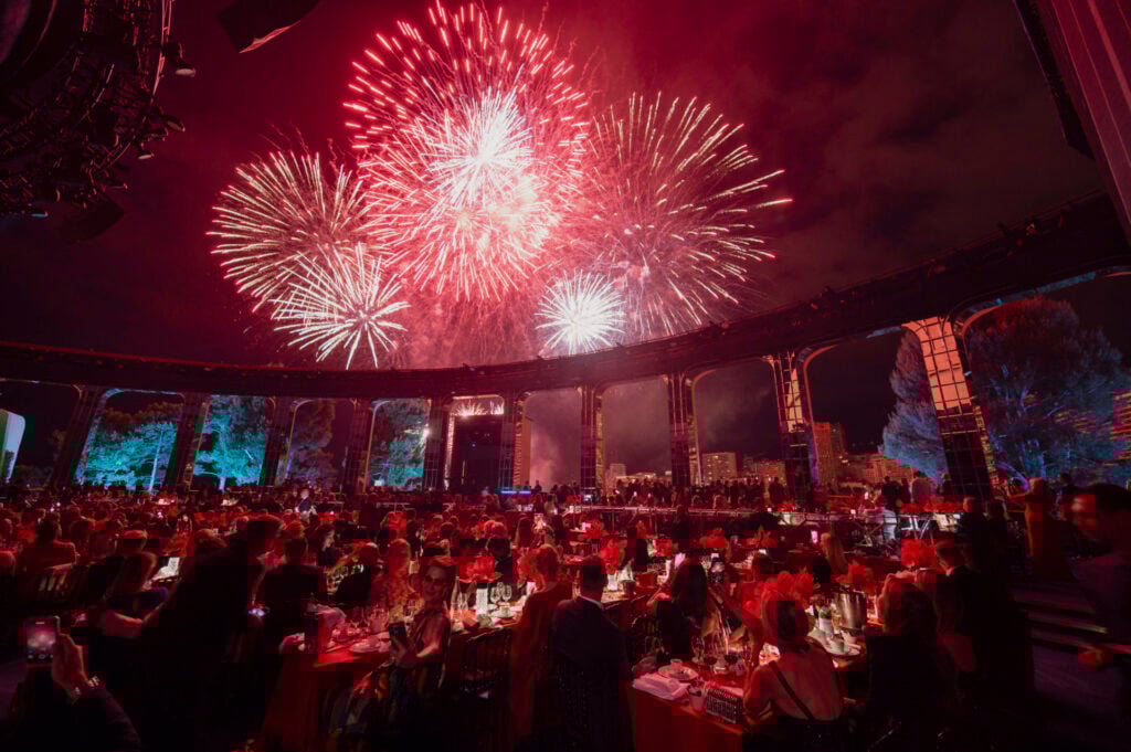 Fireworks illuminate a crowded festive dinner event.