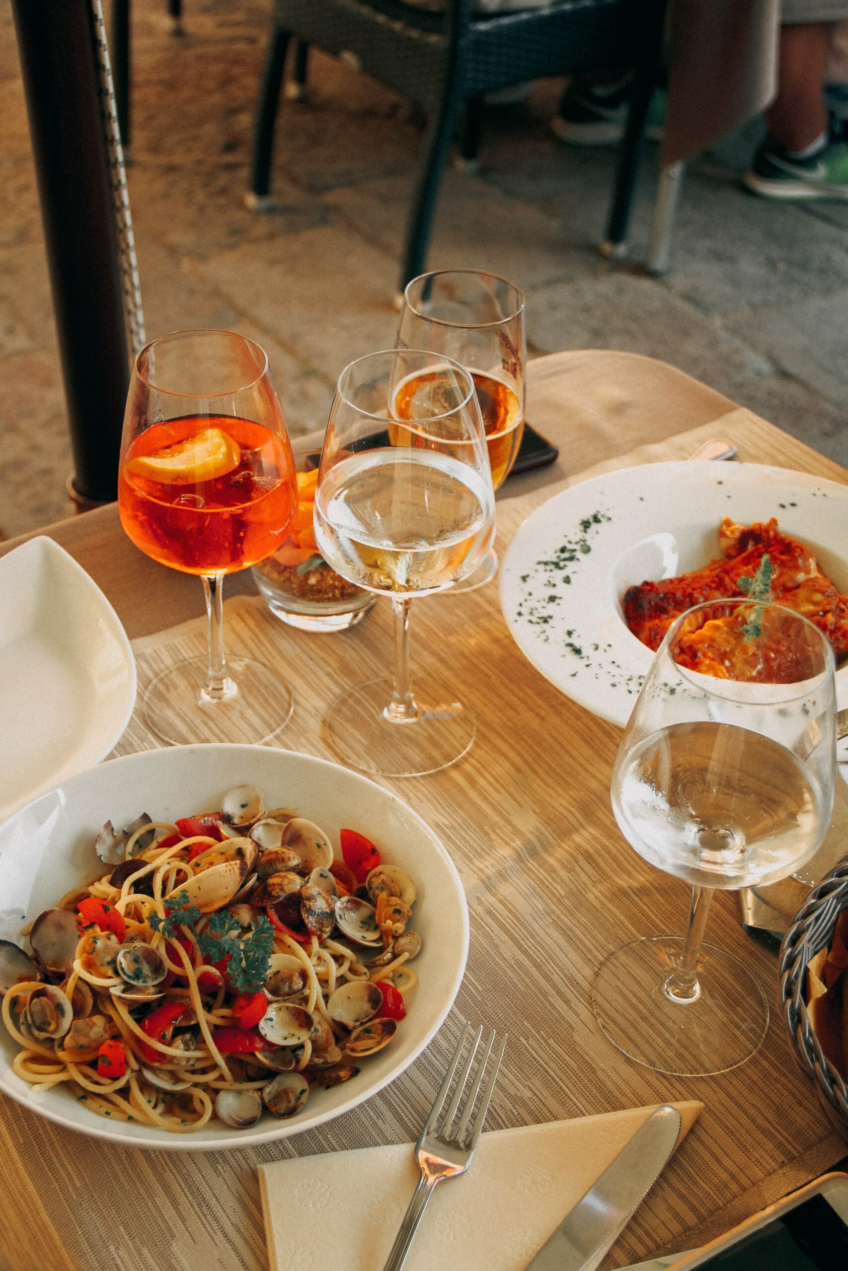 Pasta and drinks on outdoor restaurant table.