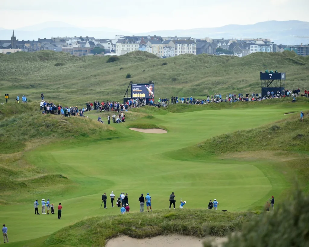 Golf course with spectators and distant buildings