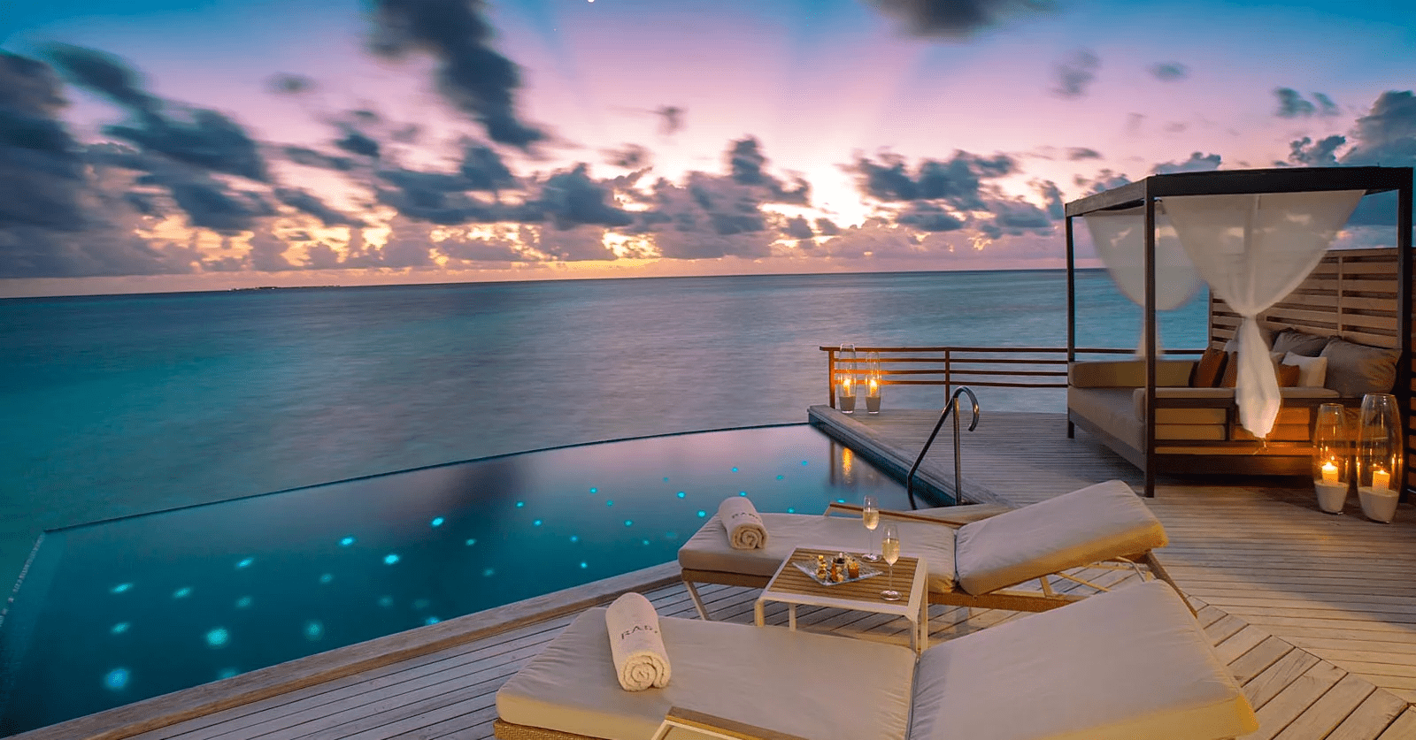 Luxury waterfront villa at sunset with pool.