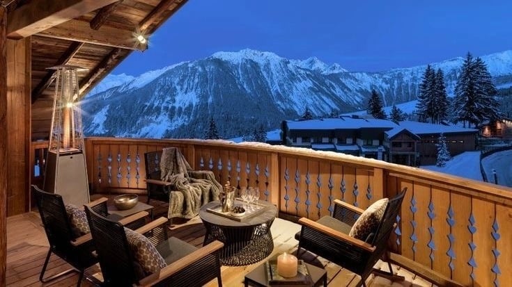 Cozy mountain cabin balcony with scenic snowy view.