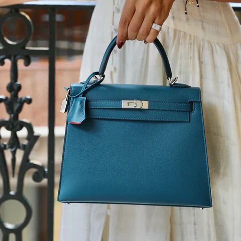 Woman holding structured blue leather handbag