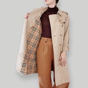 Woman wearing beige trench coat with plaid lining