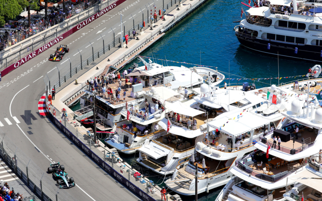 Formula 1 cars racing by luxury yachts