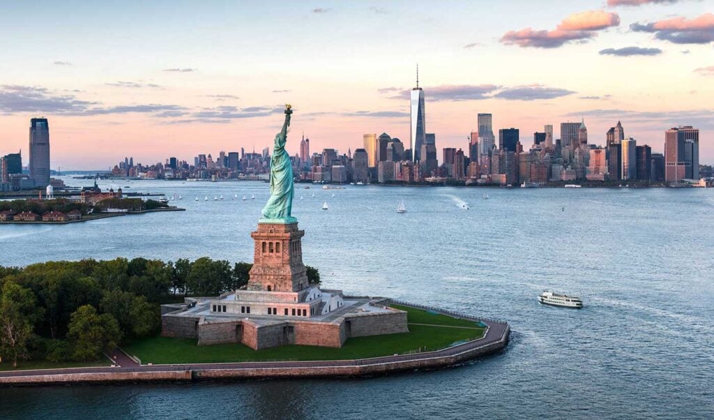 Statue of Liberty and Manhattan skyline at sunset.