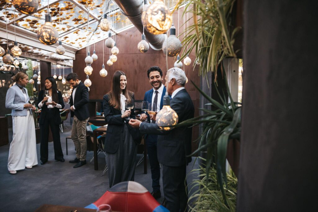 Professionals networking with wine under hanging lights