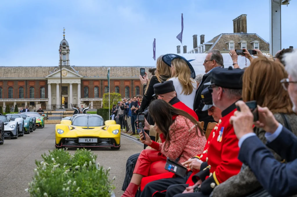 Yellow sports car at public event with spectators.