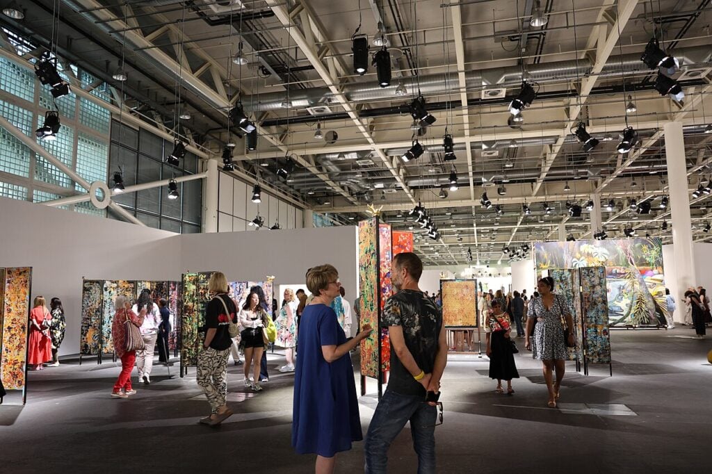 Art exhibition with people viewing colorful paintings.