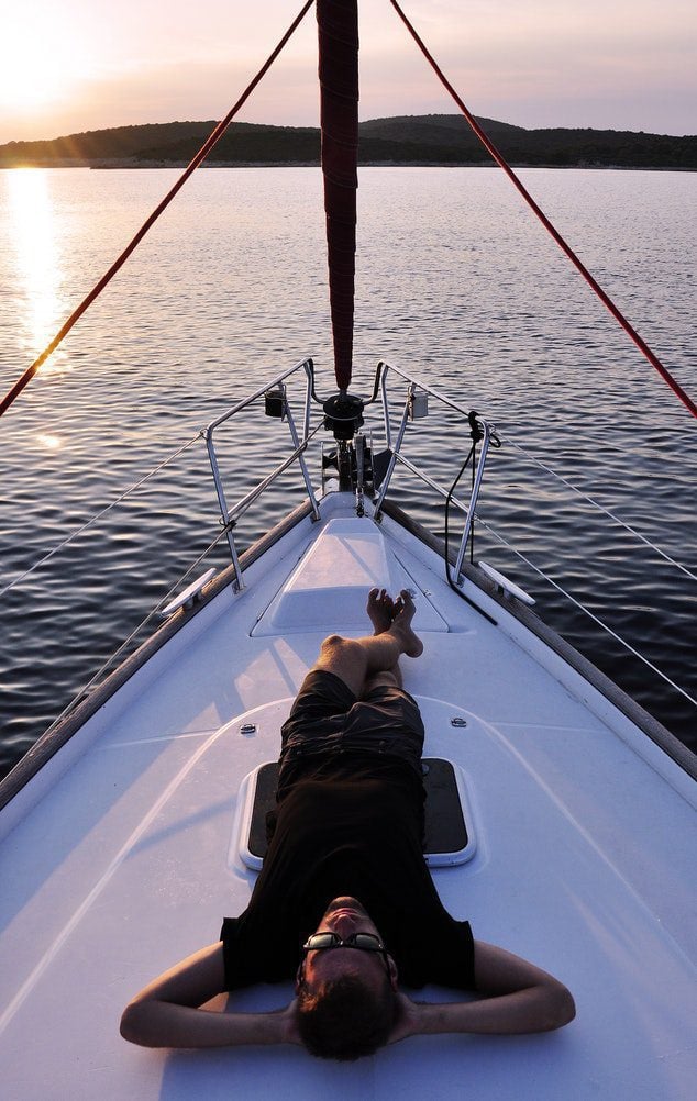 Relaxing on a sailboat at sunset on water.